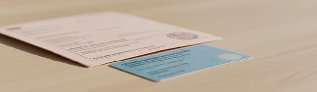 gros plan en lumière naturelle sur une table en bois clair où sont posés côte à côte un document administratif plié en t