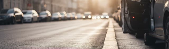 vue rasante au ras du bitume le long d'une file de voitures garées en bord de rue urbaine en fin d'après-midi, une porti